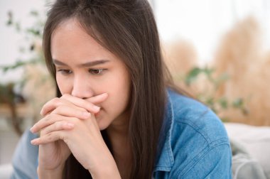 Genç Asyalı kadın evdeki oturma odasında stres hissediyor.