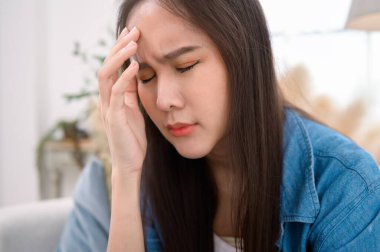 Genç Asyalı kadın evdeki oturma odasında stres hissediyor.