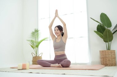 Spor giyinen, yoga yapan Asyalı bir kadın.