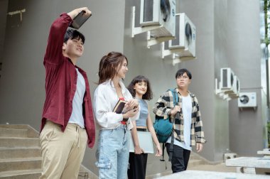 Dört öğrenci kampüste birlikte yürür, sohbet eder, kitap ve malzemelerini taşırlar..