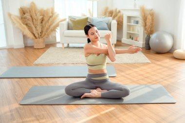 Spor giyinen, yoga yapan Asyalı bir kadın.