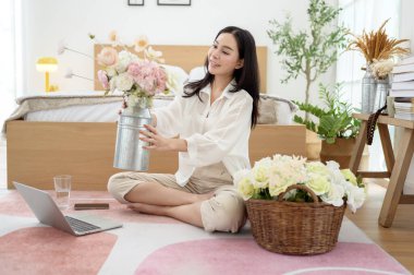 Asyalı gülümseyen kadın kavanoza güzel çiçekler koyuyor