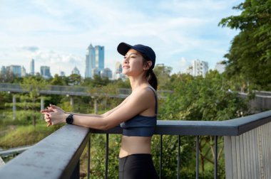 Kadın sıcak güneşin ve şehrin siluetinin tadını çıkarırken tırabzanda dinleniyor..