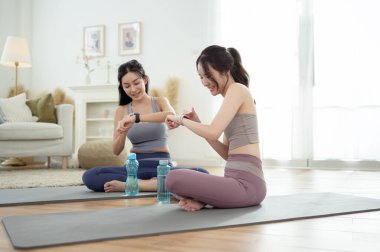 Evde yoga yaptıktan sonra rahatlayan iki genç Asyalı kadın arkadaş..