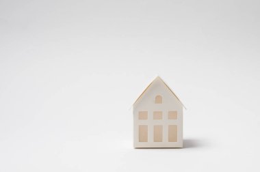 Beyaz bir yüzeydeki küçük bir ev modeli minimalist tasarımını sergiliyor..