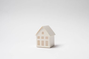 Beyaz bir yüzeydeki küçük bir ev modeli minimalist tasarımını sergiliyor..