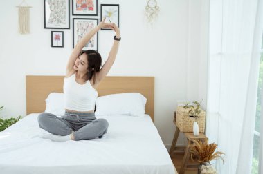 Genç Asyalı kadın yatak odasında egzersiz yapıyor.
