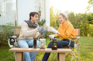 İki arkadaş bahçede dinlenir, sıcak içkilerini yudumlar ve güneşli bir günde sohbet ederler..