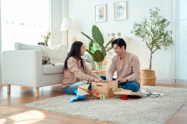 Bir çift neşeli bir şekilde kapalı alandaki bitkileri ve hasır sepetleri, parlak, havadar yaşam alanlarında tutarlar..