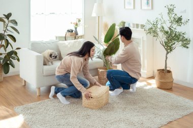 Bir çift neşeli bir şekilde kapalı alandaki bitkileri ve hasır sepetleri, parlak, havadar yaşam alanlarında tutarlar..