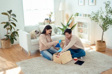 Bir çift neşeli bir şekilde kapalı alandaki bitkileri ve hasır sepetleri, parlak, havadar yaşam alanlarında tutarlar..