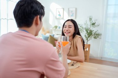 Genç bir çift, sıcak güneş ışığı ve dekorasyonlarla çevrili, neşeli bir kahvaltı yapar..