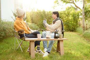 İki arkadaş gülümsüyor ve güneşli bir günde yemyeşil bir bahçede selfie için poz veriyorlar..