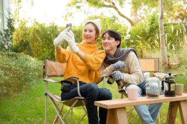 İki arkadaş gülümsüyor ve güneşli bir günde yemyeşil bir bahçede selfie için poz veriyorlar..