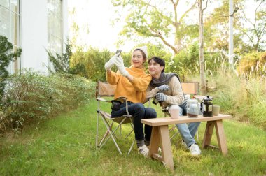 İki arkadaş gülümsüyor ve güneşli bir günde yemyeşil bir bahçede selfie için poz veriyorlar..