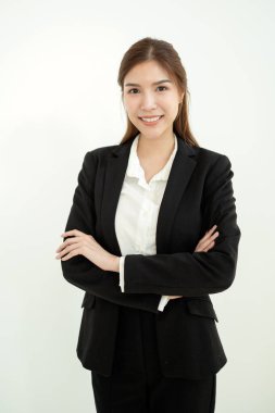 Siyah takım elbiseli kendine güvenen bir kadın kollarını kavuşturup gülümsüyor..