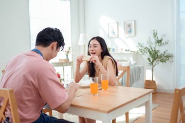Genç bir çift, sıcak güneş ışığı ve dekorasyonlarla çevrili, neşeli bir kahvaltı yapar..