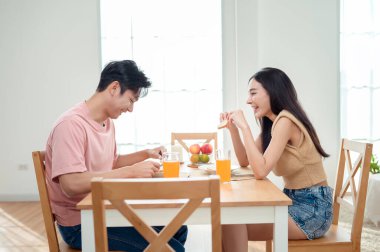 Genç bir çift, sıcak güneş ışığı ve dekorasyonlarla çevrili, neşeli bir kahvaltı yapar..