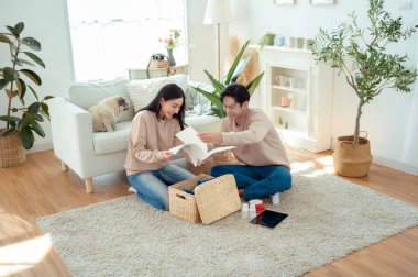 Bir çift neşeli bir şekilde kapalı alandaki bitkileri ve hasır sepetleri, parlak, havadar yaşam alanlarında tutarlar..