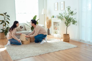 Bir çift neşeli bir şekilde kapalı alandaki bitkileri ve hasır sepetleri, parlak, havadar yaşam alanlarında tutarlar..