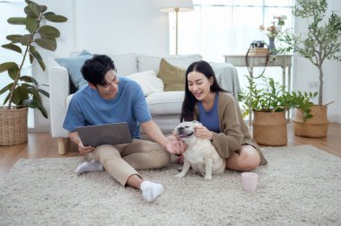 Genç bir çift, köpekleriyle bir kanepede rahatlar. Parlak bir yaşam alanında keyifli anlar paylaşırlar..