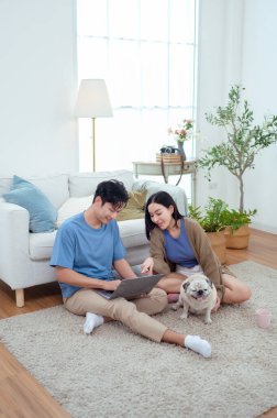 Genç bir çift, köpekleriyle bir kanepede rahatlar. Parlak bir yaşam alanında keyifli anlar paylaşırlar..