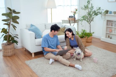 Genç bir çift, köpekleriyle bir kanepede rahatlar. Parlak bir yaşam alanında keyifli anlar paylaşırlar..