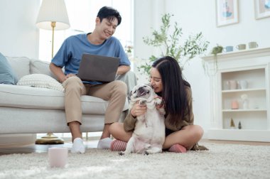 Genç bir çift, köpekleriyle bir kanepede rahatlar. Parlak bir yaşam alanında keyifli anlar paylaşırlar..