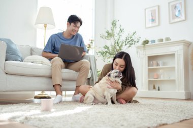 Genç bir çift, köpekleriyle bir kanepede rahatlar. Parlak bir yaşam alanında keyifli anlar paylaşırlar..