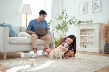 Genç bir çift, köpekleriyle bir kanepede rahatlar. Parlak bir yaşam alanında keyifli anlar paylaşırlar..