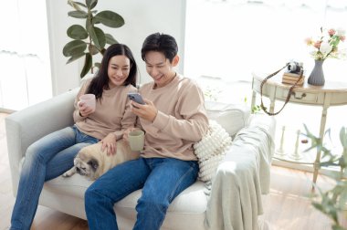 Genç bir çift, neşeli köpekleriyle vakit geçirir. Parlak, bitki dolu bir oturma odasında..