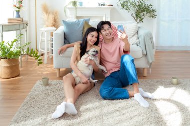 Genç bir çift, neşeli köpekleriyle vakit geçirir. Parlak, bitki dolu bir oturma odasında..