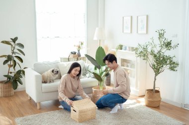 Bir çift neşeli bir şekilde kapalı alandaki bitkileri ve hasır sepetleri, parlak, havadar yaşam alanlarında tutarlar..