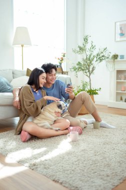 Genç bir çift, neşeli köpekleriyle vakit geçirir. Parlak, bitki dolu bir oturma odasında..