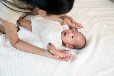 Bir anne, yumuşak bir yatakta şefkat gösteren bebeğiyle hassas bir anı paylaşır..