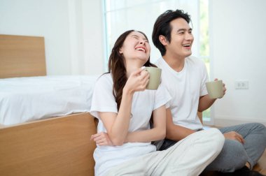 Sabah ışığıyla dolu bir yatak odasında iki kişi kahkaha atıp kahve yudumluyor..