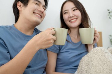 Sabah ışığıyla dolu bir yatak odasında iki kişi kahkaha atıp kahve yudumluyor..