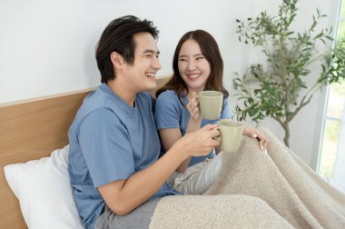 Sabah ışığıyla dolu bir yatak odasında iki kişi kahkaha atıp kahve yudumluyor..