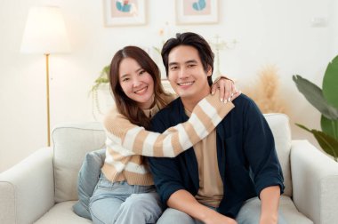 Genç bir çift kanepede dinleniyor. Parlak bir oturma odasında bitkilerle keyifli bir anı paylaşıyorlar..