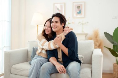 Genç bir çift kanepede dinleniyor. Parlak bir oturma odasında bitkilerle keyifli bir anı paylaşıyorlar..