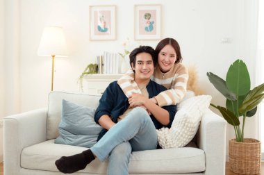 Genç bir çift kanepede dinleniyor. Parlak bir oturma odasında bitkilerle keyifli bir anı paylaşıyorlar..