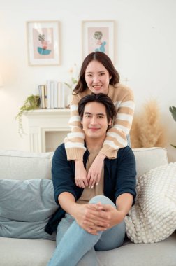 Genç bir çift kanepede dinleniyor. Parlak bir oturma odasında bitkilerle keyifli bir anı paylaşıyorlar..