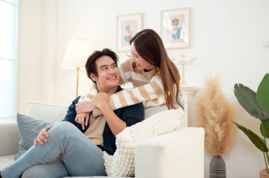 Genç bir çift kanepede dinleniyor. Parlak bir oturma odasında bitkilerle keyifli bir anı paylaşıyorlar..