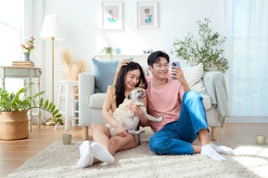 Genç bir çift, neşeli köpekleriyle vakit geçirir. Parlak, bitki dolu bir oturma odasında..