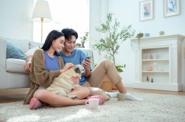 Genç bir çift, neşeli köpekleriyle vakit geçirir. Parlak, bitki dolu bir oturma odasında..