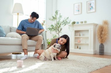 Genç bir çift, köpekleriyle bir kanepede rahatlar. Parlak bir yaşam alanında keyifli anlar paylaşırlar..