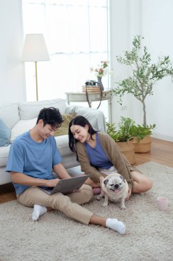 Genç bir çift, köpekleriyle bir kanepede rahatlar. Parlak bir yaşam alanında keyifli anlar paylaşırlar..