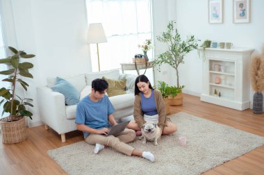 Genç bir çift, köpekleriyle bir kanepede rahatlar. Parlak bir yaşam alanında keyifli anlar paylaşırlar..