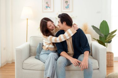 Genç bir çift kanepede dinleniyor. Parlak bir oturma odasında bitkilerle keyifli bir anı paylaşıyorlar..