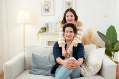 Genç bir çift kanepede dinleniyor. Parlak bir oturma odasında bitkilerle keyifli bir anı paylaşıyorlar..